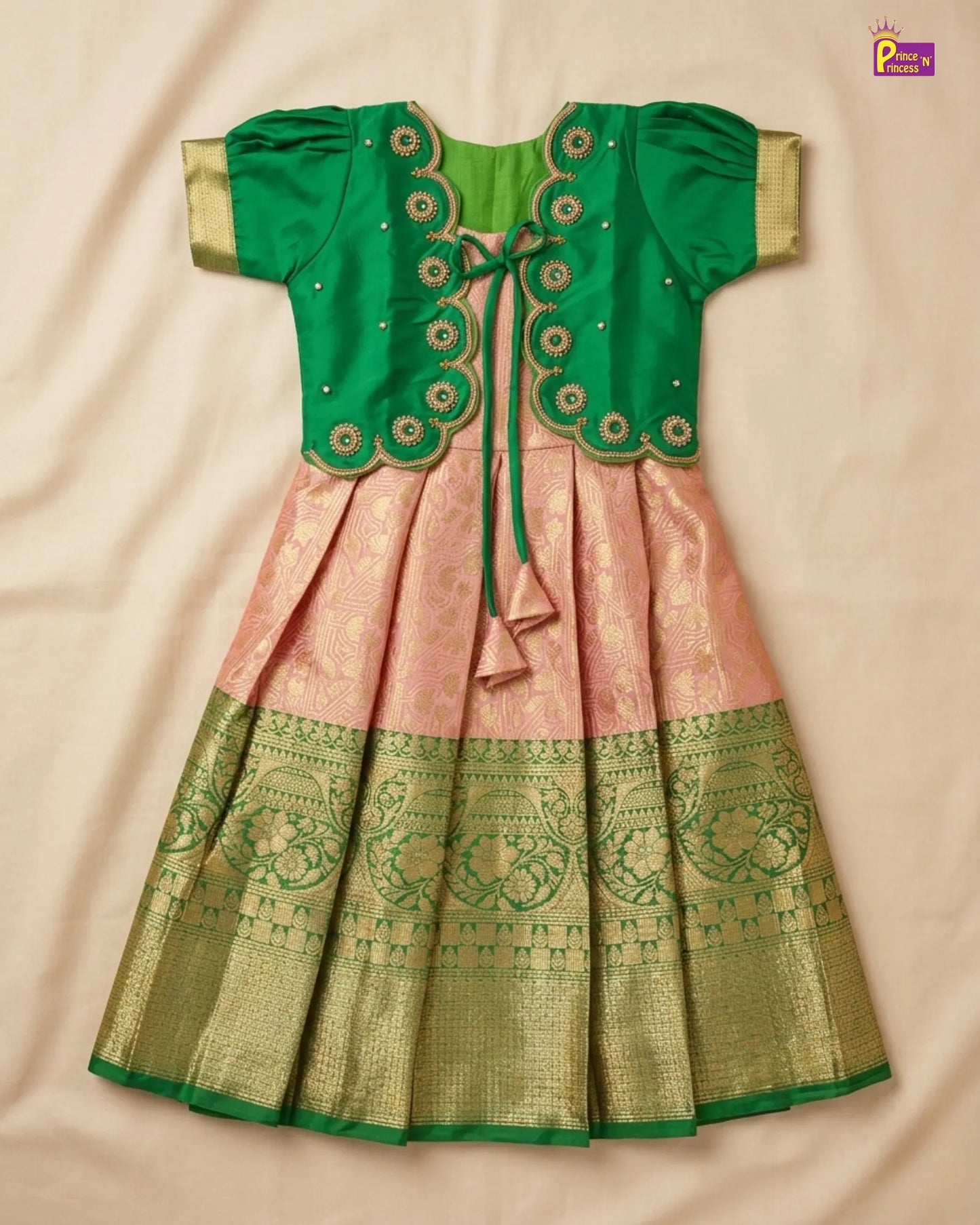 Green and pink traditional outfit with intricate patterns on a beige background