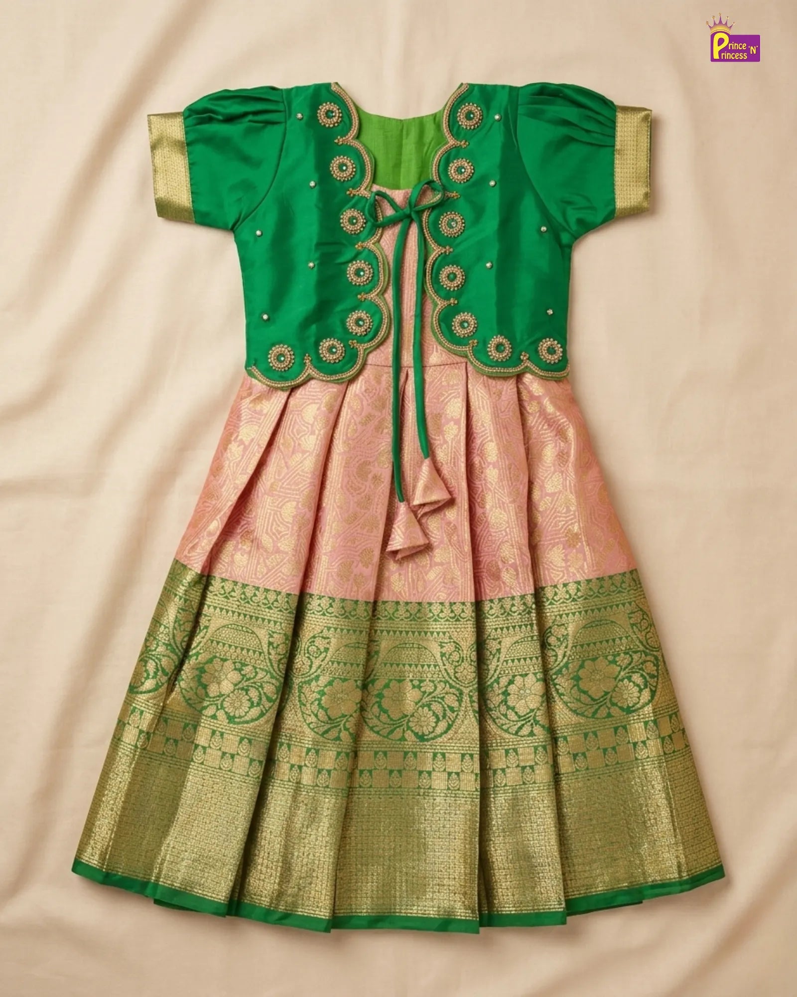 Green and pink traditional outfit with intricate patterns on a beige background
