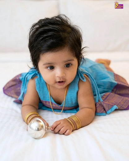 Baby in traditional outfit holding a toy on a white background