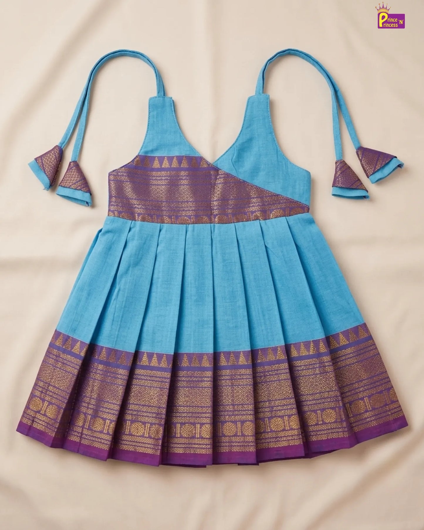 Blue and purple traditional dress with matching apron on a beige background
