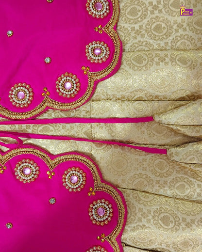 A close-up of a traditional Indian outfit fabric, featuring a bright pink dupatta with gold zari embroidery and mirror work, paired with a beige and gold brocade saree body.