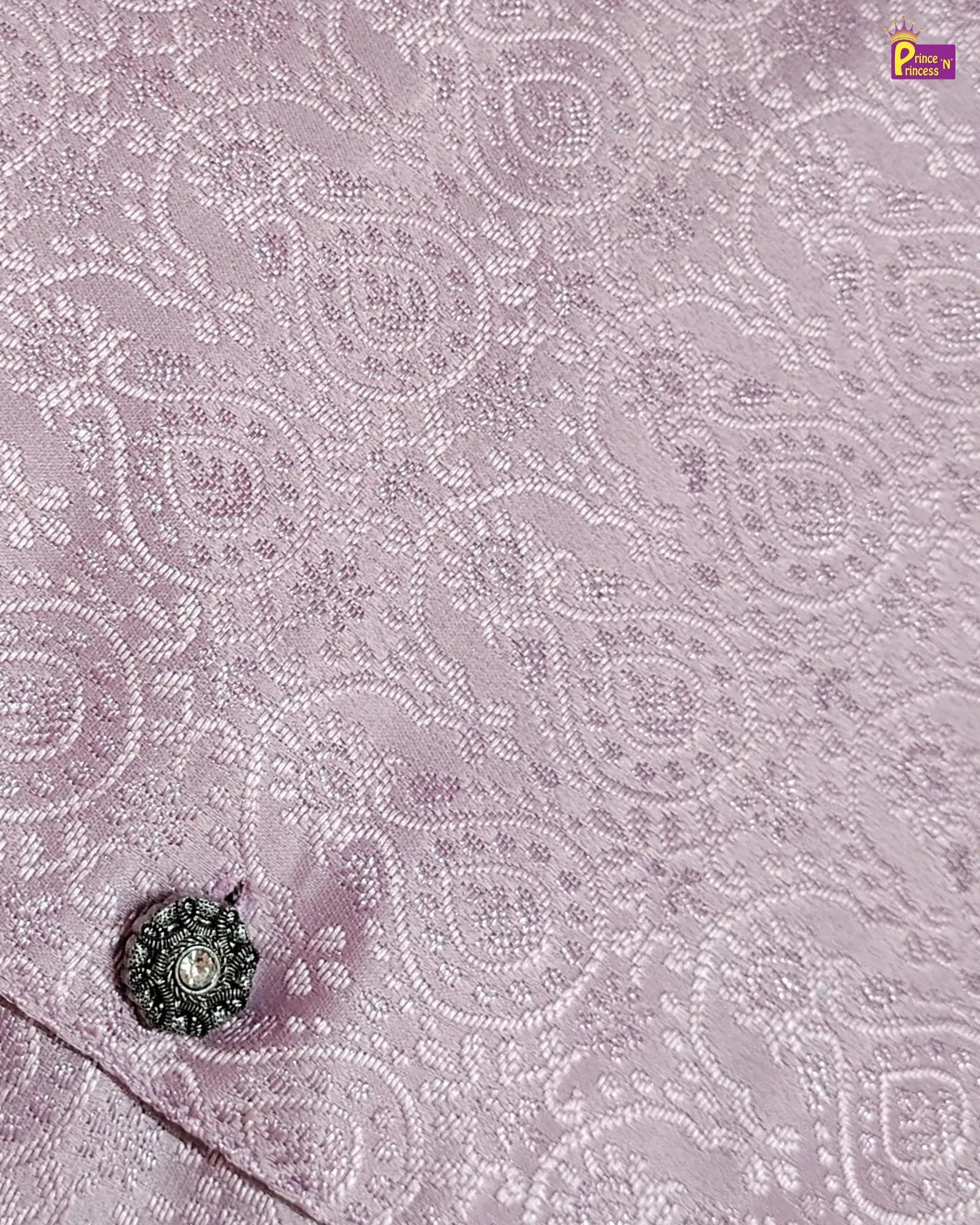 Close-up of a pink fabric with intricate white embroidery and a decorative button.