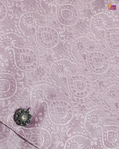 Close-up of a pink fabric with intricate white embroidery and a decorative button.