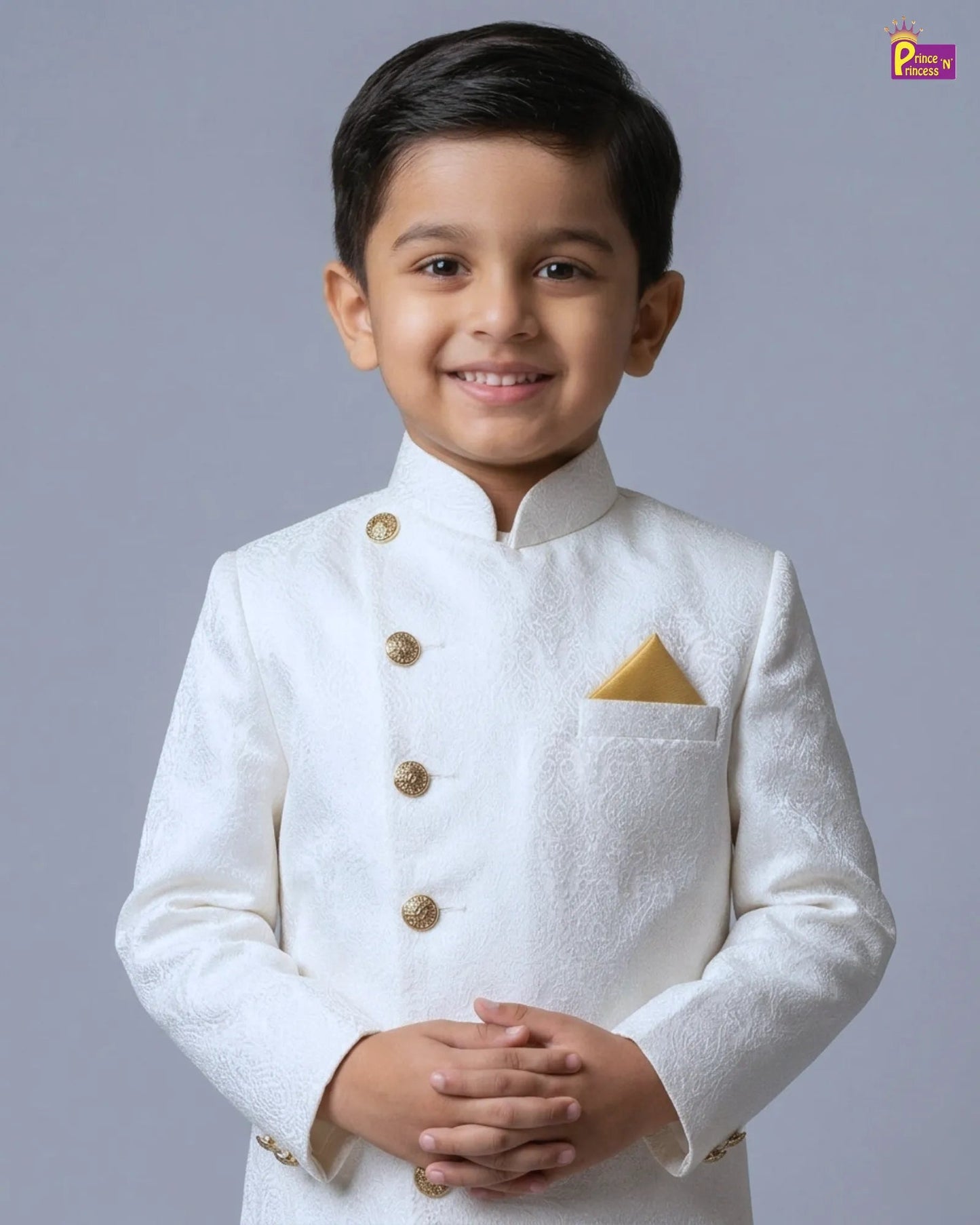 Young boy wearing a white traditional outfit with gold buttons on a gray background