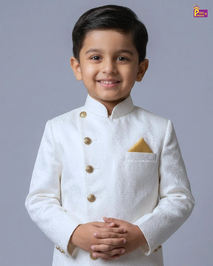 Young boy wearing a white traditional outfit with gold buttons on a gray background