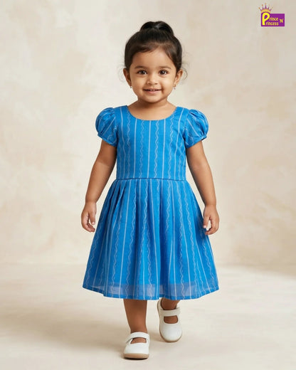 Young girl wearing a blue dress with white stripes on a beige background
