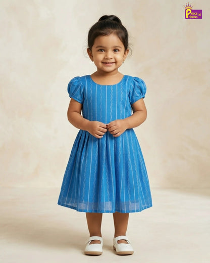 Young girl wearing a blue dress with white stripes on a beige background