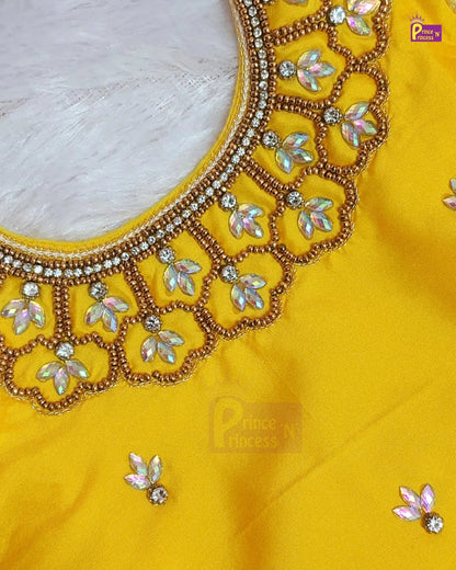 Close-up of a bright yellow fabric garment with ornate gold beaded neckline embroidery, iridescent floral embellishments, and small matching floral details on the fabric.