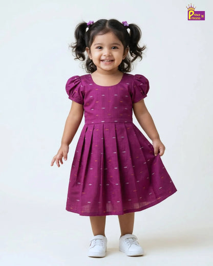 Child wearing a purple dress with white polka dots on a white background