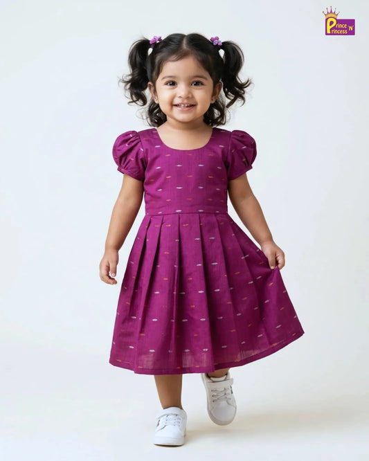 Child wearing a purple dress with white patterns on a white background