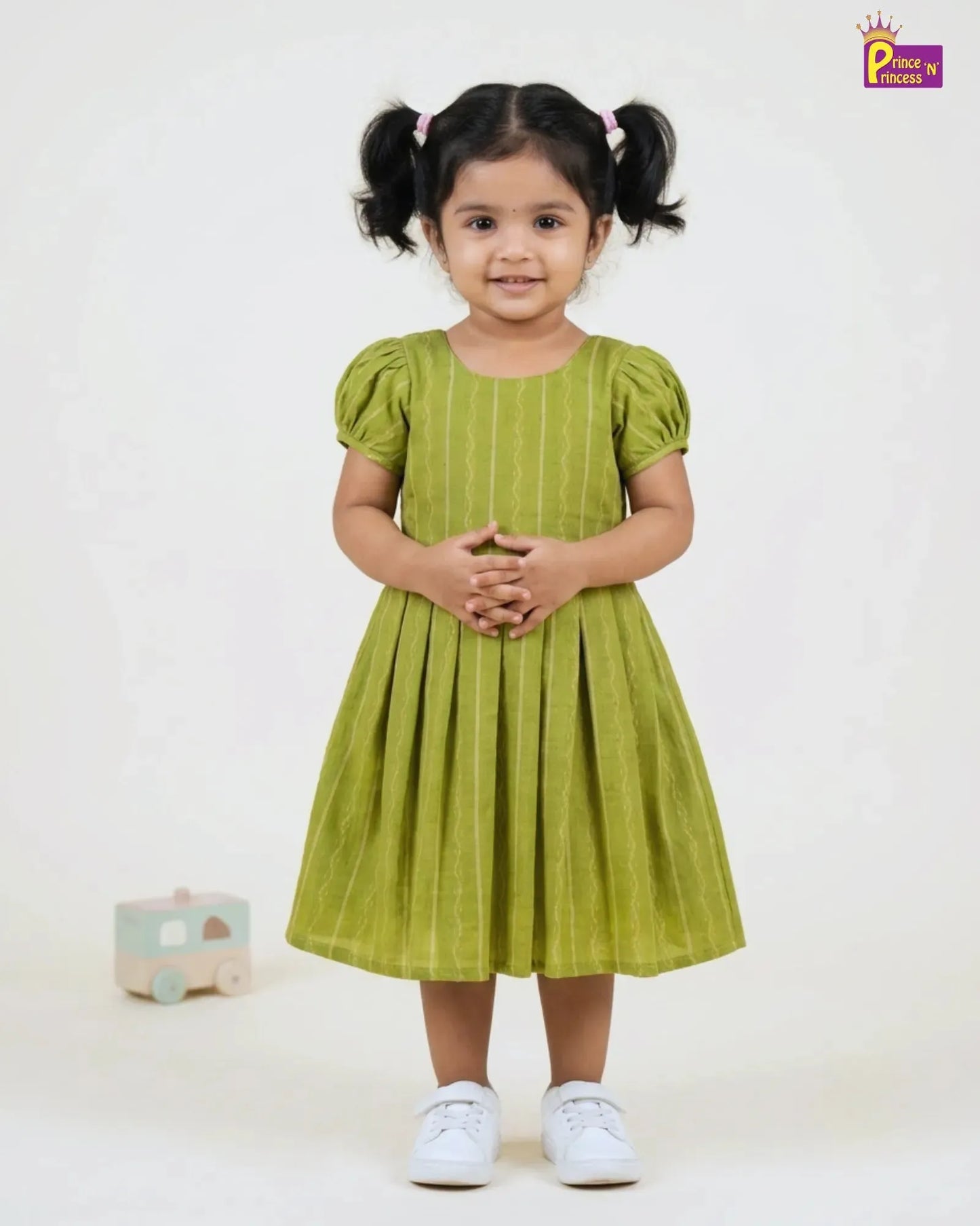 Young girl wearing a green dress with pigtails on a white background