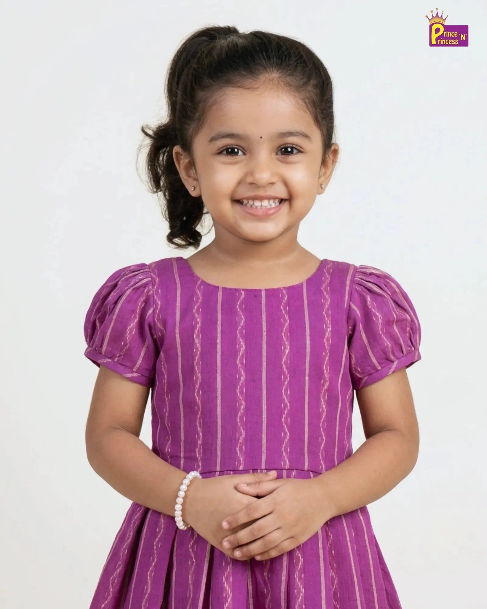 Young girl wearing a purple dress with white patterns on a white background
