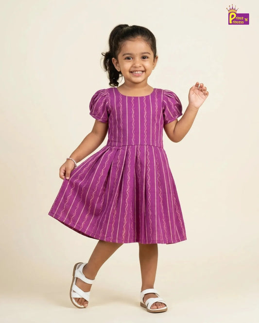 Young girl wearing a purple dress with white patterns on a beige background