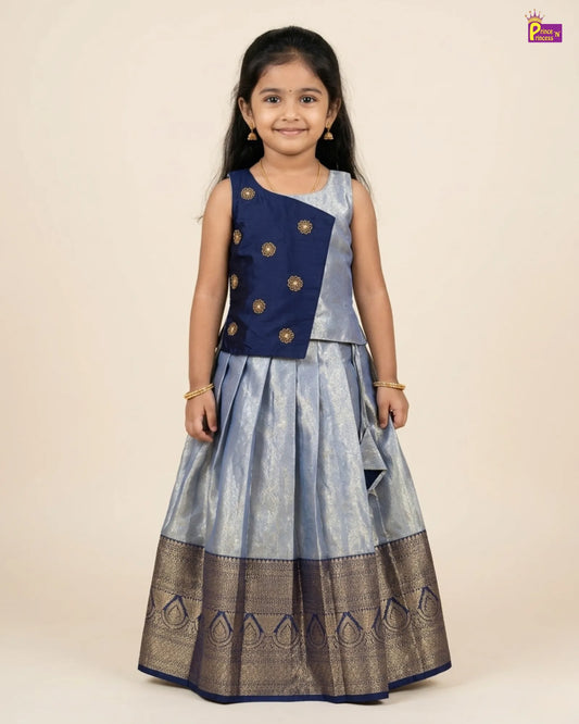 Young girl wearing a traditional outfit with a blue and gray top and skirt on a beige background