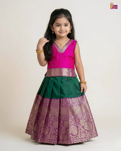 Young girl wearing a traditional outfit with a pink top and green and purple skirt on a white background