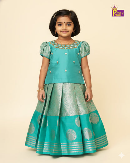 Young girl wearing a traditional turquoise outfit with intricate designs on a beige background